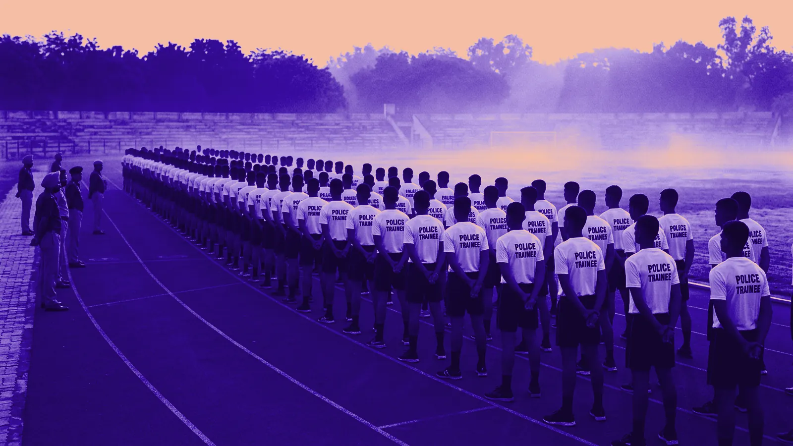 Police trainees standing in a line on a running track at dawn